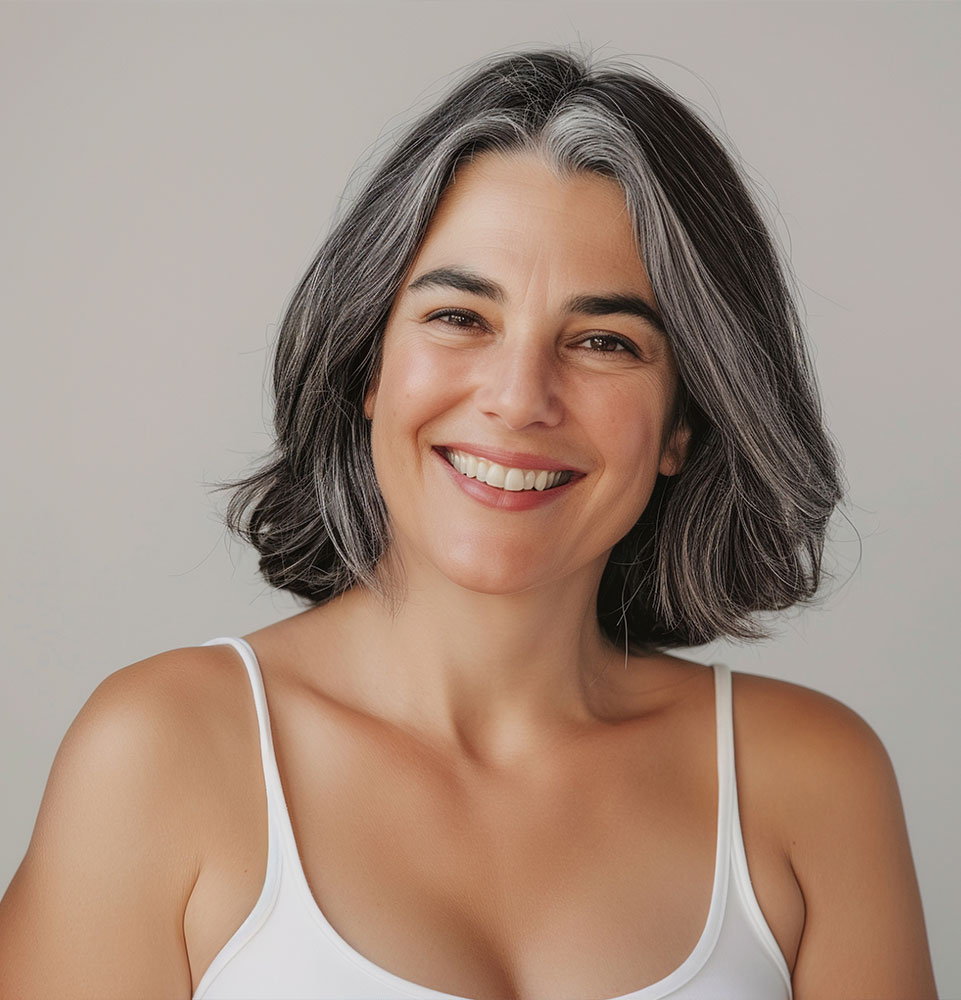 Studio portrait of happy and attractive mature woman with gray hair, smiling and wearing white tank top