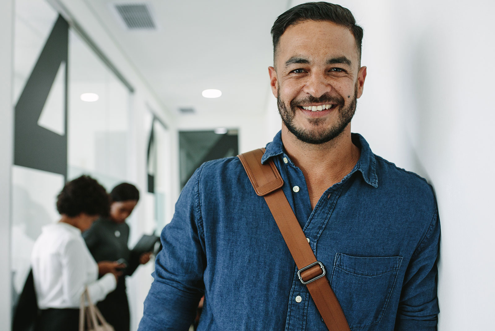 person smiling brightly in a crowded work office hallway
